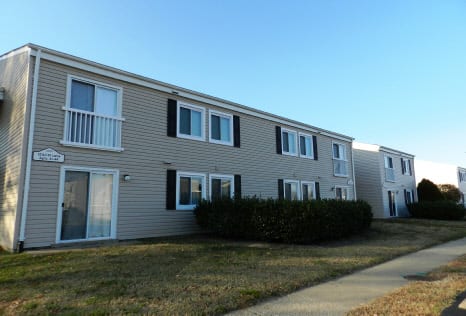 Two-story Village Green apartment buildings and lawn on a clear winter day